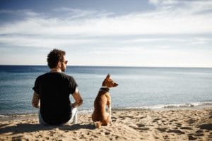 man with dog at beach recovering through Oceanfront Recovery's residential treatment program