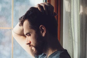 man considering addiction treatment programs while looking out window