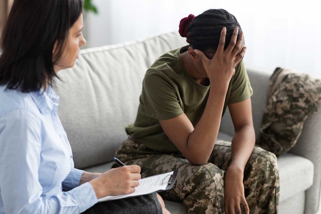 Therapist talks to veteran who puts hand up to face as she talks about her ptsd