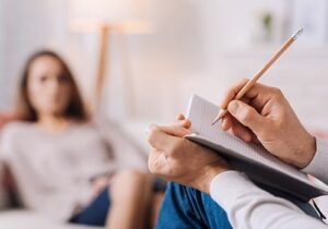Doctor takes notes while talking to woman who has entered a depression treatment program